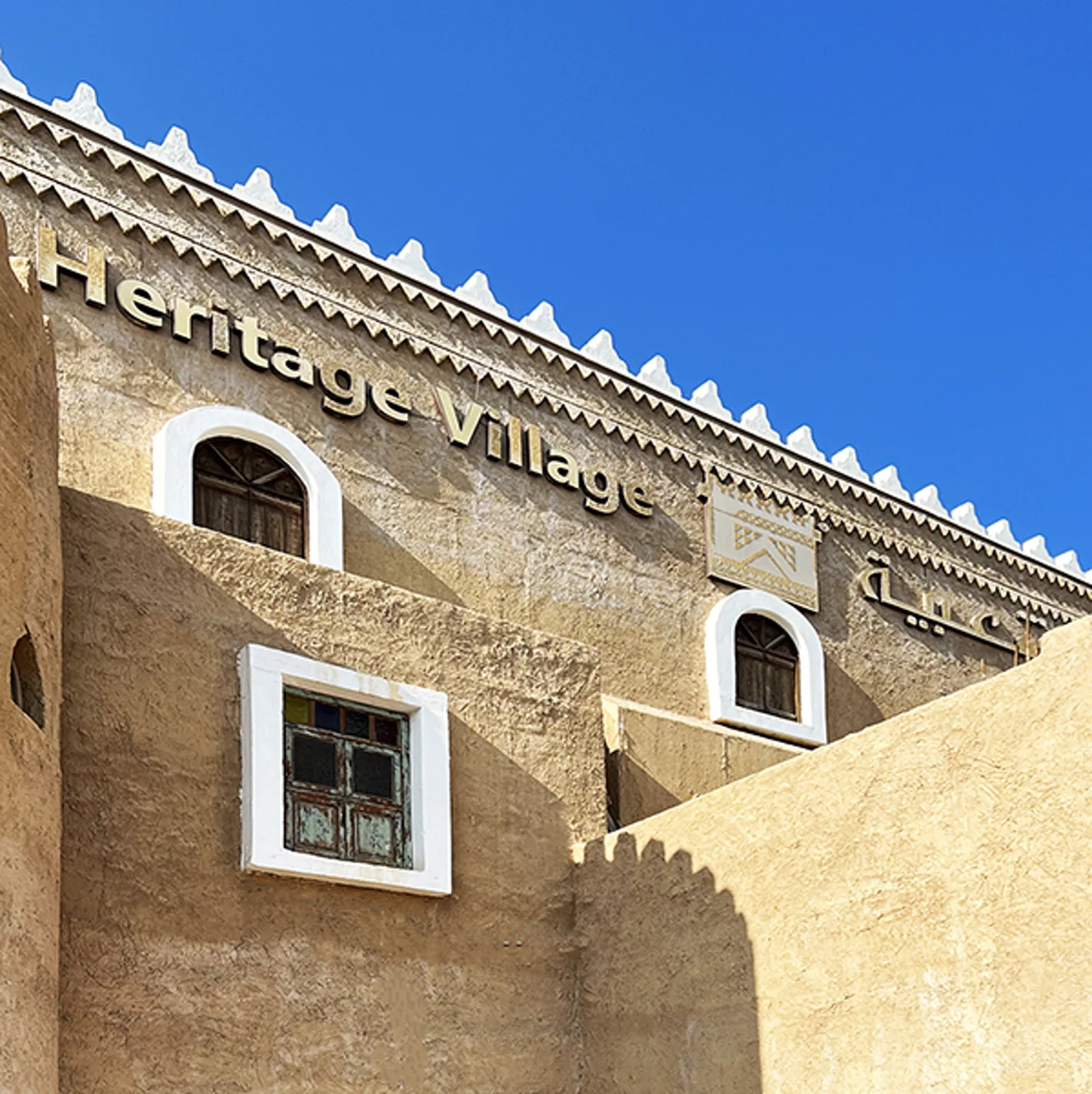 Adobe-style facade of Heritage Village on the Dammam Corniche, with Arabic signage